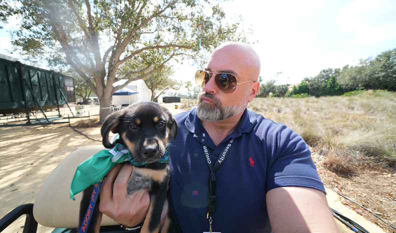 A Chubb security officer drives a pup around in a golf cart while snuggling it